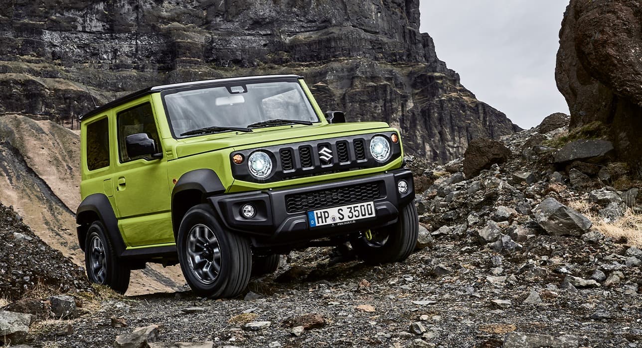 Abbildung zeigt einen grünen Jimny, der einen steinigen Hand hinauf fährt
