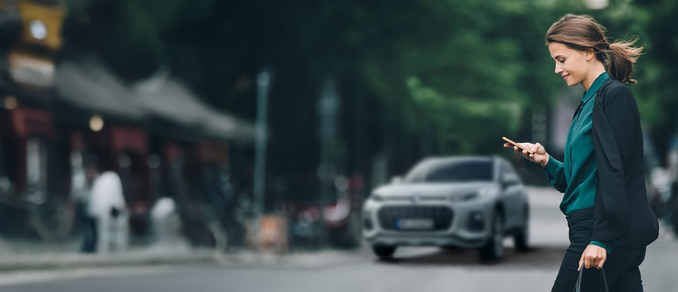 Abbildung zeigt eine Frau auf einer Straße mit einem Handy in der Hand