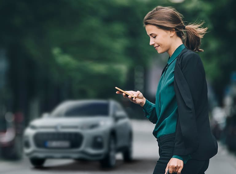 Abbildung zeigt eine Frau auf einer Straße mit einem Handy in der Hand