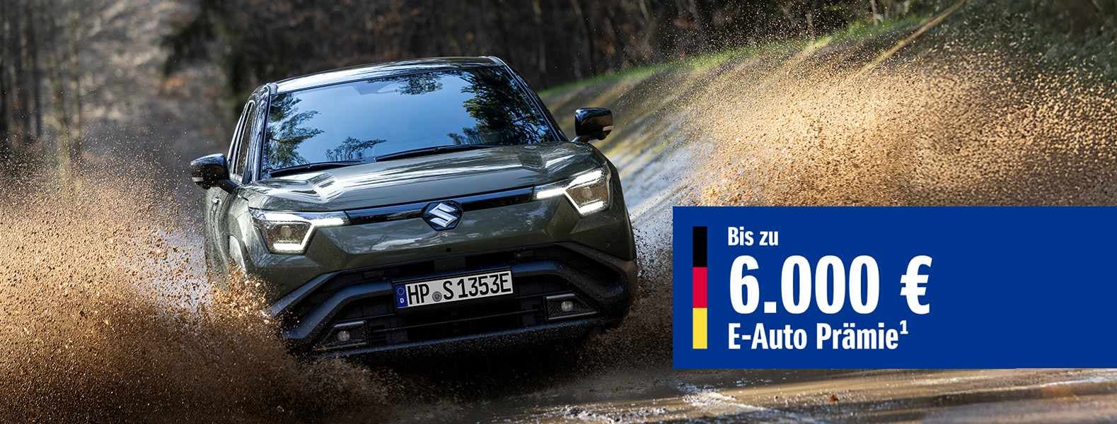 Dunkelgrüner Suzuki e Vitara fährt durch Matsch